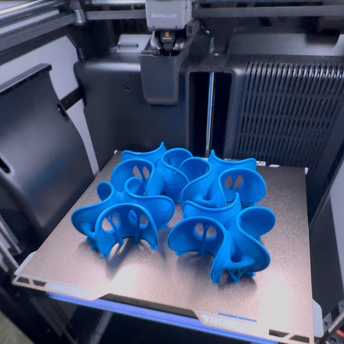 Blue 3D printed objects on a 3D printer bed
