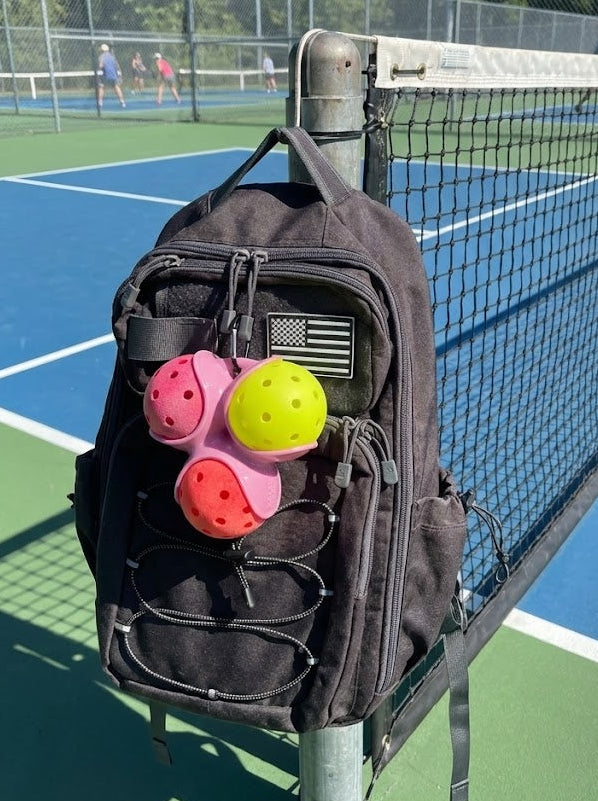 Black backpack with colorful pickleball paddles on a tennis court