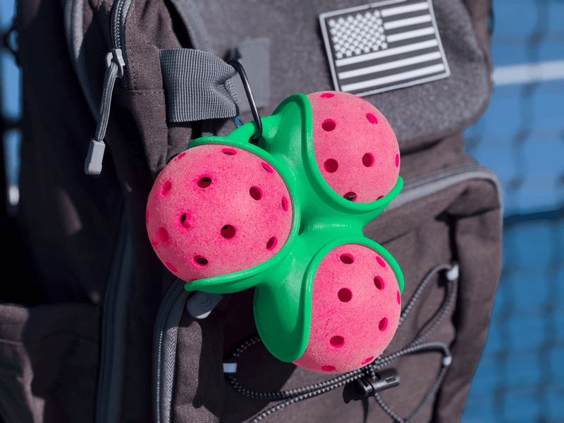 Green Pickle Pocket attached to a black bag on a pickleball court.